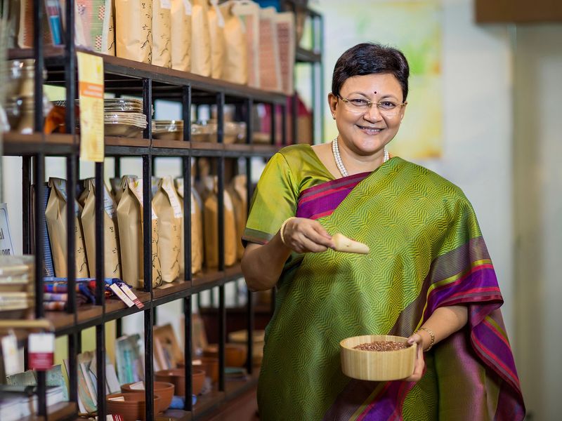 A shop owner standing among stocked shelves in her store